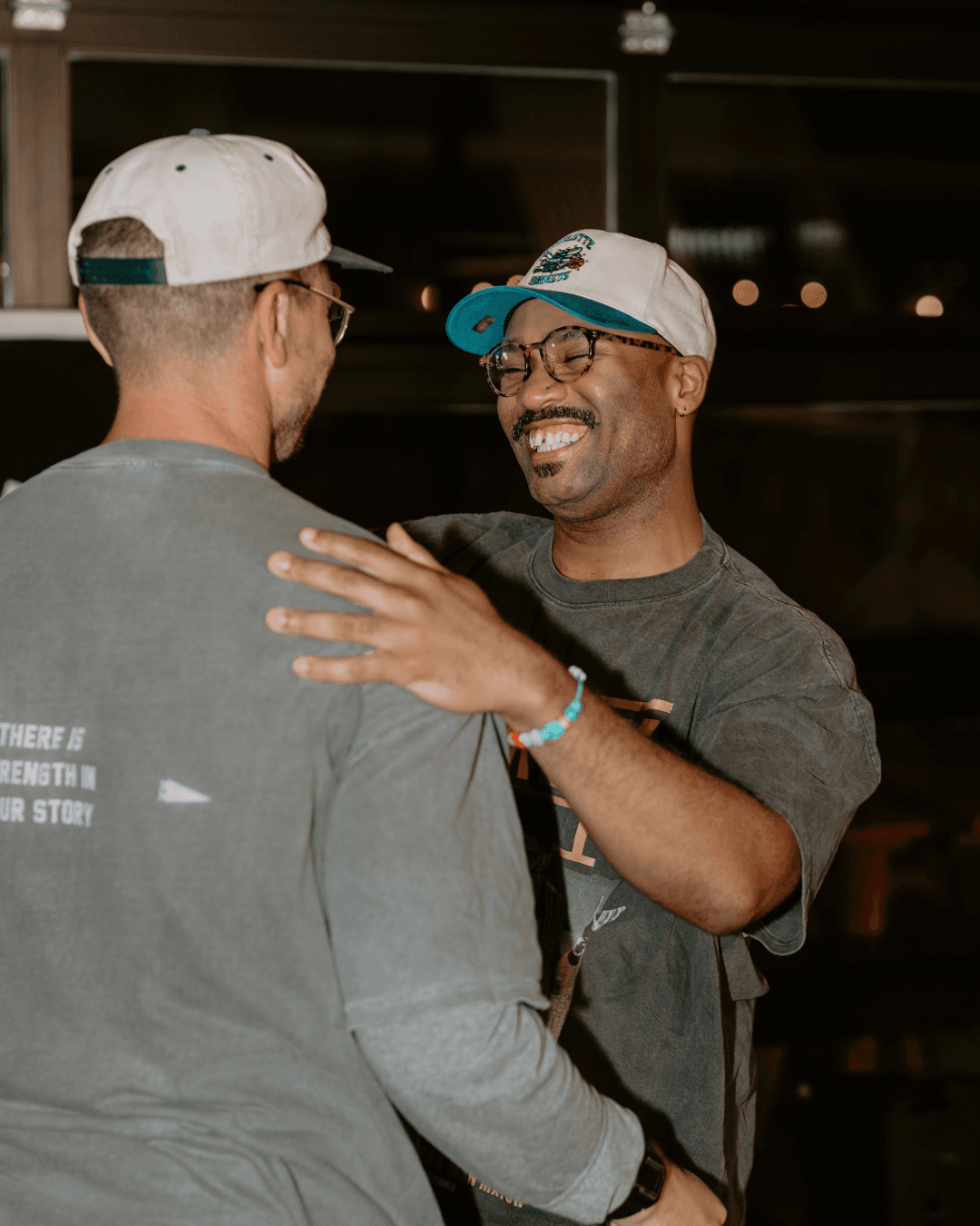 black man smiling and hugging a white man at a scatter joy event that supports mental health care and makes it more affordable and accessible for people