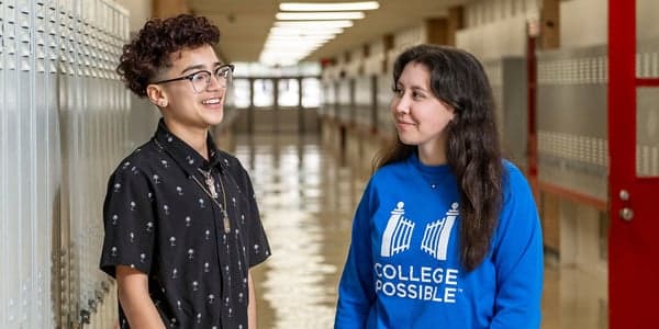 A College Possible coach and student talk in a school hallway.